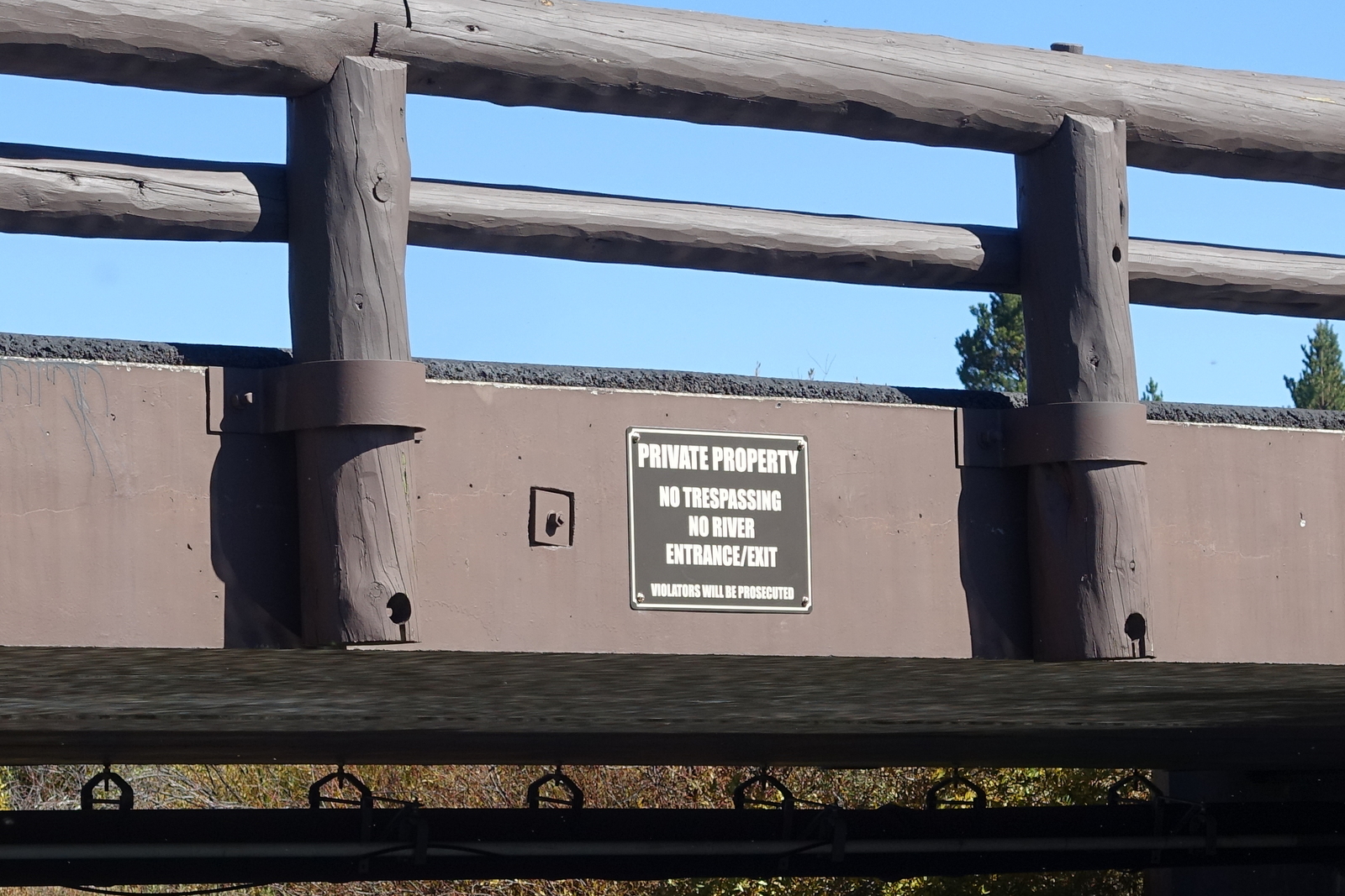 No trespassing sign on ranch log-railed bridge
